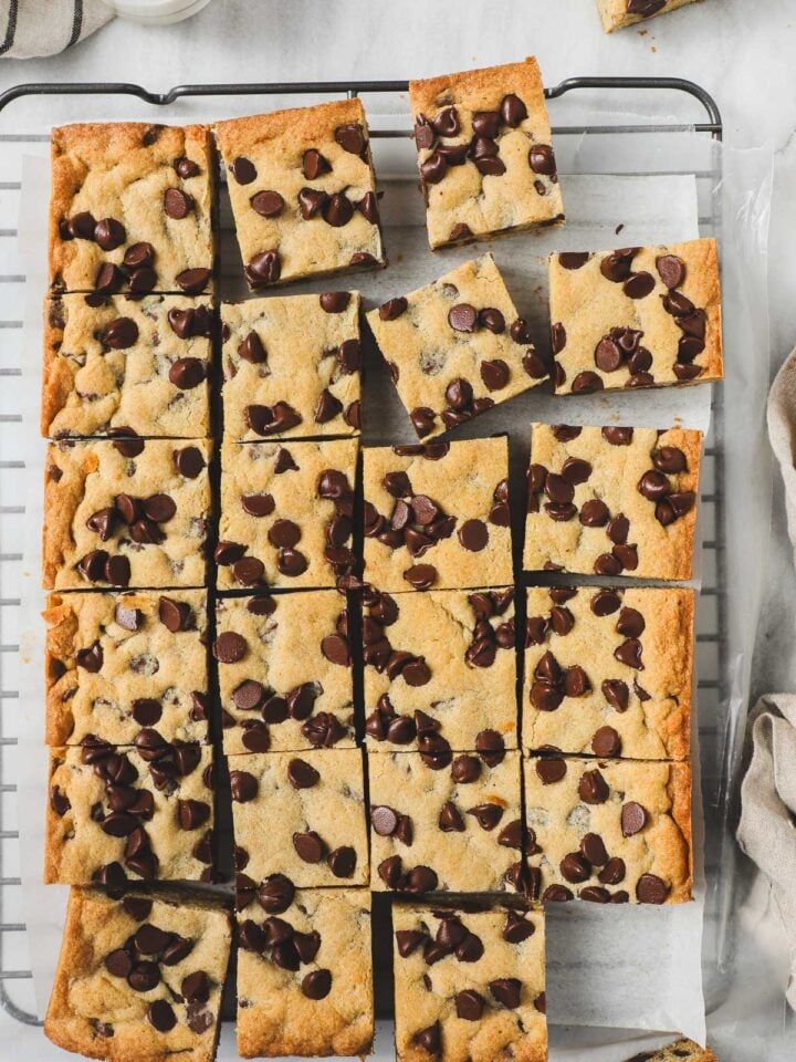 Chocolate Chip Cookie Bars removed from a 9x13 pan and cut into 24 squares laying flat on parchment paper on a cookie drying rack.