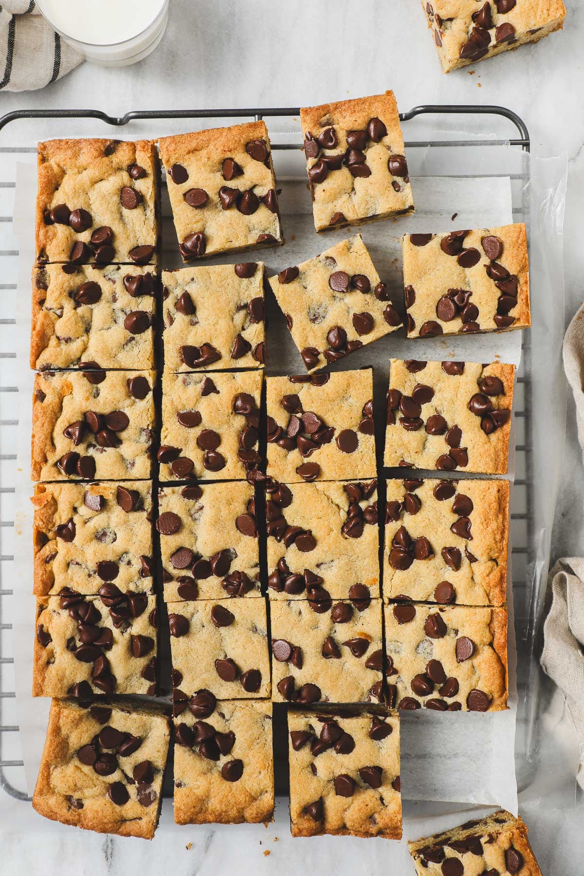 Chocolate Chip Cookie Bars removed from a 9x13 pan and cut into 24 squares laying flat on parchment paper on a cookie drying rack.